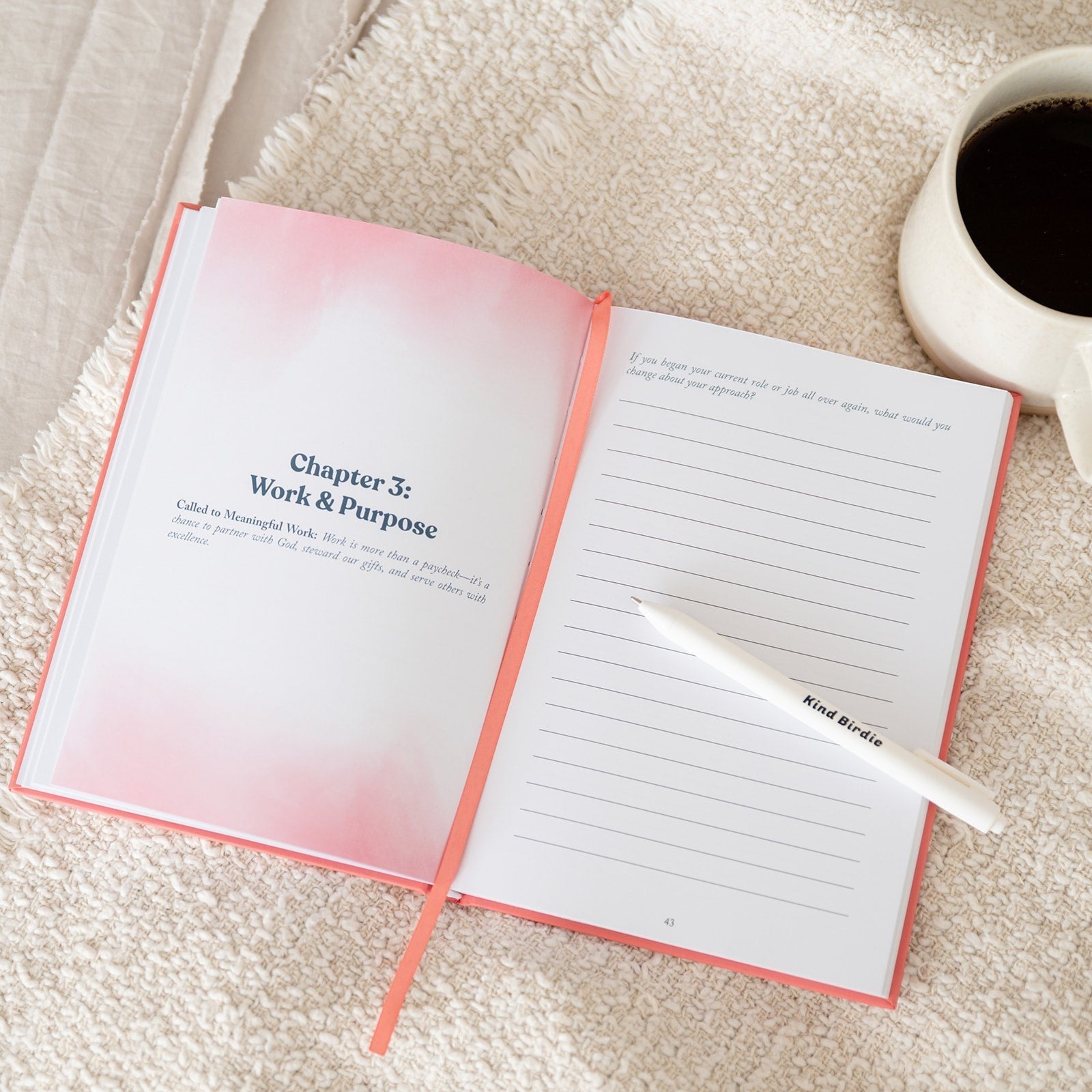The Aligned Journal by Kind Birdie, a guided journal for personal realignment with prompts on work and purpose. White pen rests on lined pages.