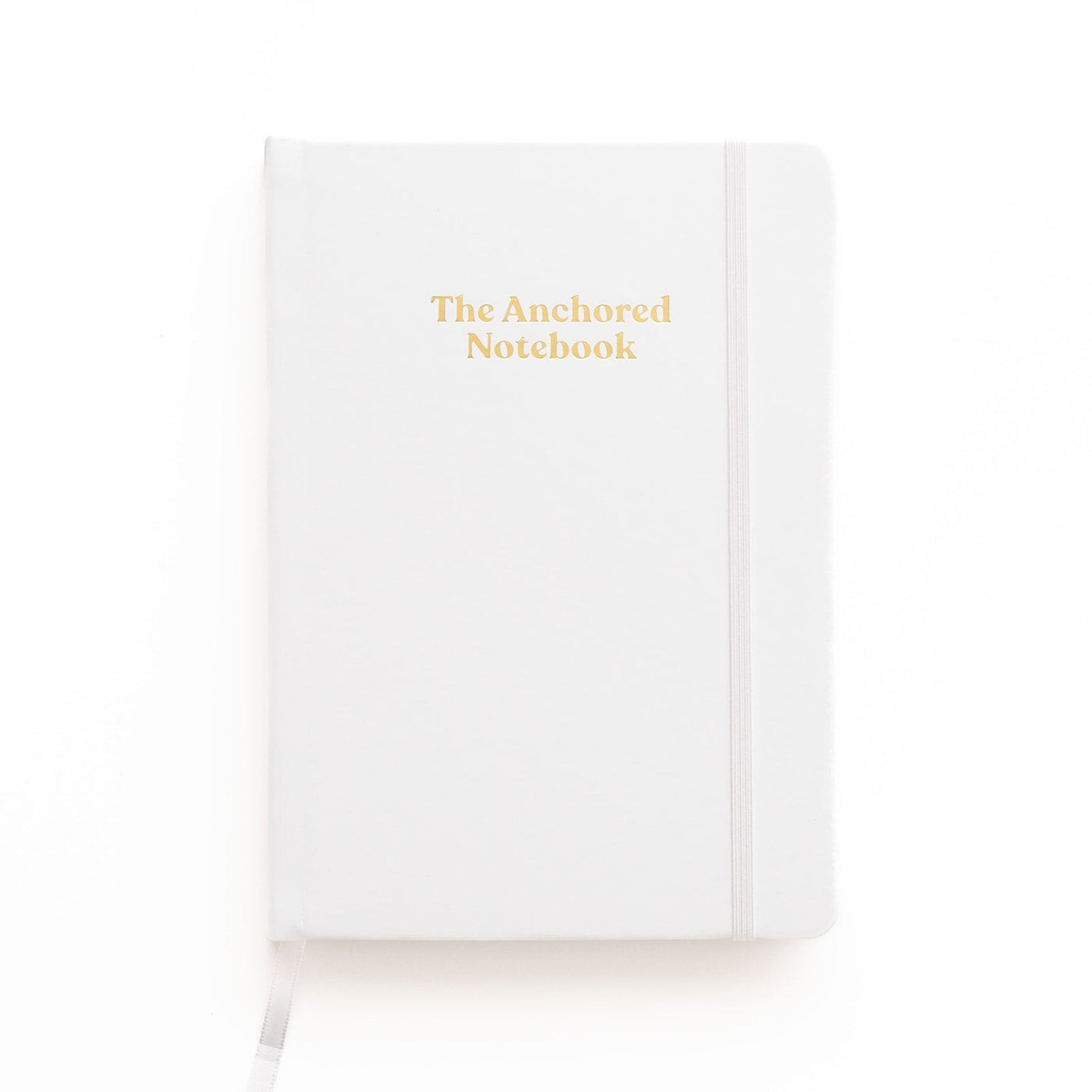 Kind Birdie The Anchored Notebook, a white blank journal with gold lettering and an elastic band closure.